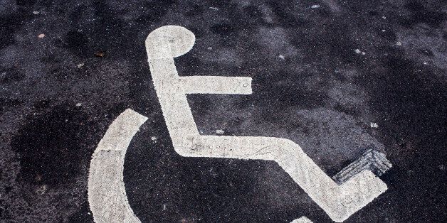 Wheelchair figure stenciled in white lines on tarmac as a sign for a disabled parking bay Middlesborough, England, UK. (Photo by In Pictures Ltd./Corbis via Getty Images)