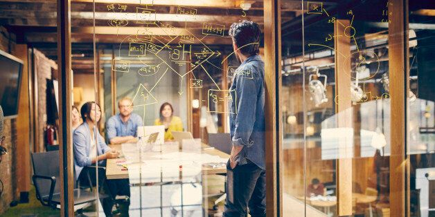 A team of young professionals discuss a project in modern office meeting room.