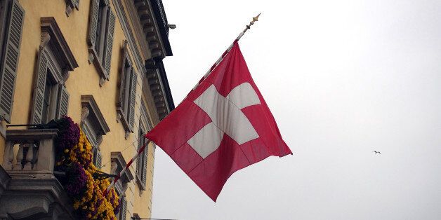 A Swiss national flag flies on the side of a residential building in Lugano, Switzerland, on Tuesday, Nov. 15, 2016. While the Swiss National Bank (SNB) admitted to interventions to weaken the franc following the Brexit referendum, it declined to comment after the U.S. election last week. Photographer: Stephen Kelly/Bloomberg via Getty Images