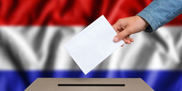 Election in Netherlands. The hand of woman putting her vote in the ballot box. Dutch flag on background.