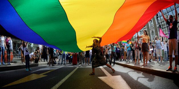A woman dances under a huge rainbow flag during the Gay Pride parade in Belgrade on September 18, 2016. The Belgrade Gay Pride parade, the third in a row since the event was marred by violence in 2010, was held without incidents amid tight security as thousands of riot police officers were deployed in the city center. / AFP / Oliver BUNIC (Photo credit should read OLIVER BUNIC/AFP/Getty Images)