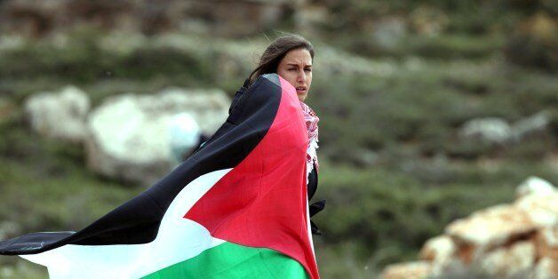 A woman holds up the Palestinian flag during clashes with Israeli soldiers close to the Jewish settlement of Beit El, in the Israeli occupied West Bank, on March 11, 2014. The clashes broke out following the funeral of Saji Sayel Darwish who was killed the previous day by Israeli soldiers during fighting with stone throwers near the West Bank administrative centre of Ramallah. AFP PHOTO / ABBAS MOMANI (Photo credit should read ABBAS MOMANI/AFP/Getty Images)