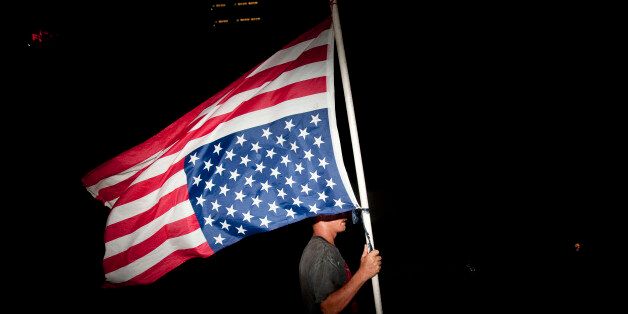 TAMPA, FL - AUGUST 30: A protester with an upside-down American flag marches on the last night of the Republican National Convention in Tampa, Florida on August 30, 2012. The Republican party delegates affirmed Mitt Romney as the party's nominee for president August 28. (Photo by Edward Linsmier/Getty Images)