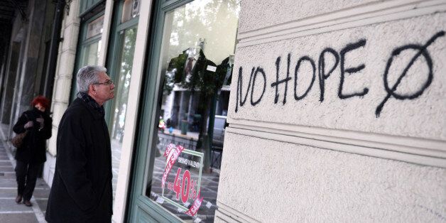 A man looks at a window shop in central Athens next to a slogan reading' No hope' on January 31, 2017. / AFP / LOUISA GOULIAMAKI (Photo credit should read LOUISA GOULIAMAKI/AFP/Getty Images)