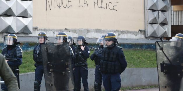 Policemen stand next to a graffiti reading 'fuck the police' in front of the local police station in Aulnay-sous-Bois, northern Paris, on February 6, 2017 during a protest a day after a French police officer was charged with the rape of a youth who was severely injured after allegedly being sodomized with a baton.Clashes between young protesters and police forces sparked for the second evening and left several cars burnt and five people in custody in Aulnay-sous-Bois. A French police officer was charged on February 5, 2017, with the rape of a youth in a high-rise Paris suburb who was severely injured after allegedly being sodomized with a baton. Three other officers were also charged with assault over the arrest of a 22-year-old man on February 2, during an identity check in a multi-ethnic housing estate in Aulnay-sous-Bois, north of the capital. / AFP / FRANCOIS GUILLOT (Photo credit should read FRANCOIS GUILLOT/AFP/Getty Images)