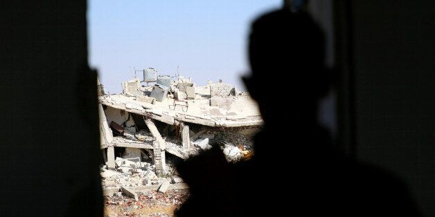 A Free Syrian Army fighter looks out at a damaged building in Al-Yadudah village, in Deraa Governorate, Syria July 8, 2016. Picture taken July 8, 2016. REUTERS/Alaa Al-Faqir