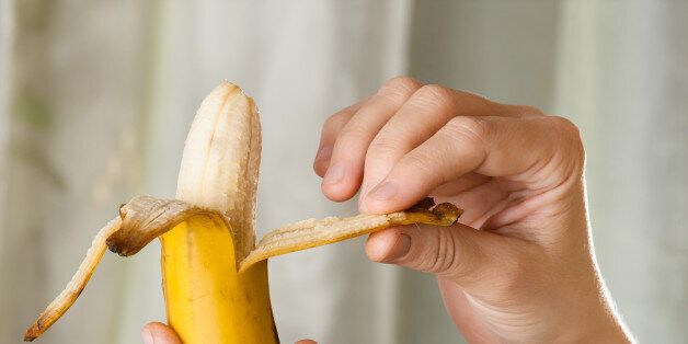 hands peeling ripe yellow banana, close up