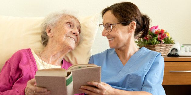 Female nurse with senior woman patient, reading a book