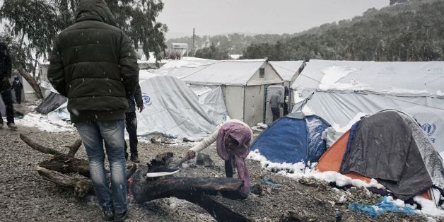 Migrants try to light a fire during snowfall at the Moria hotspot on the Greek island of Lesbos, on January 9, 2017.With more than 60,000 mainly Syrian refugees on its territory, Greece has moved many migrants to prefabricated houses and heated tents, but on the island of Lesbos in Moria hotspot there are 'more than 2,500 people living in tents, without hot water or heating, including women, children and handicapped people,' said Apostolos Veizis from the charity Doctors Without Borders. / AFP / STR (Photo credit should read STR/AFP/Getty Images)