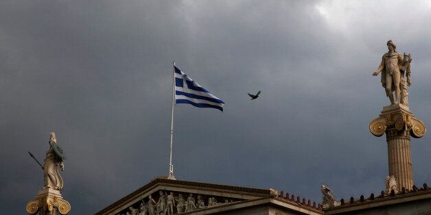 A Greek national flag flutters atop the university building as dark clouds fill the sky in Athens, Greece, June 30, 2015. Greece's conservative opposition warned on Tuesday that Sunday's vote over international bailout terms would be a referendum over the country's future in Europe, and that wages and pensions would be threatened if people were to reject the package. REUTERS/Yannis Behrakis