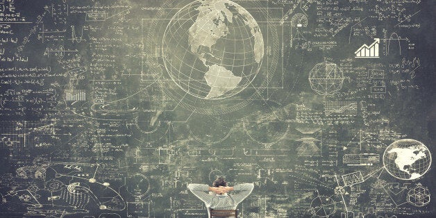 Businessman sitting on a chair and studying math formulas on blackboard
