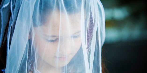 Little girl dressed as a bride with veil over the face