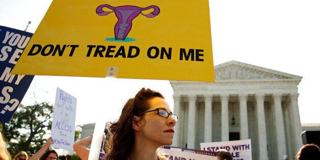 Demonstrators hold signs outside the U.S. Supreme Court as the court is due to issue its first major abortion ruling since 2007 against a backdrop of unremitting divisions among Americans on the issue and a decades-long decline in the rate at which women terminate pregnancies in Washington, U.S. June 27, 2016. REUTERS/Kevin Lamarque