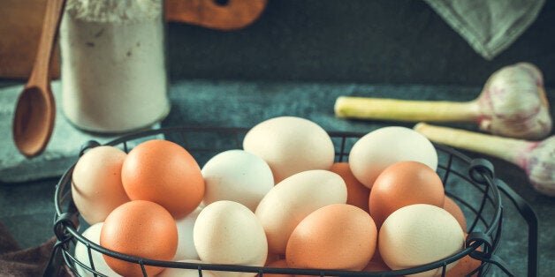 Eggs in wire basket on rustic table horizontal. Toned