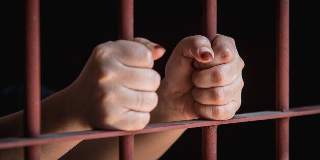 hands of muslim woman holding bars in jail