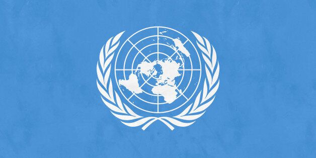A white UN emblem (world map surrounded by two olive branches) on a blue background.