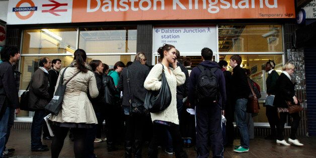 A woman speaks on a mobile phone as people queue to enter Dalston Kingsland overground station during rush hour in London October 4, 2010. London commuters struggled to get to work on Monday as workers on the city's underground rail network held their second 24-hour strike in a month in a dispute over planned job cuts. Most of the capital's underground lines were suspended or partly suspended because of a walkout by up to 10,000 Tube staff that began late on Sunday. REUTERS/Simon Newman (BRITAIN - Tags: BUSINESS EMPLOYMENT TRANSPORT TRAVEL)