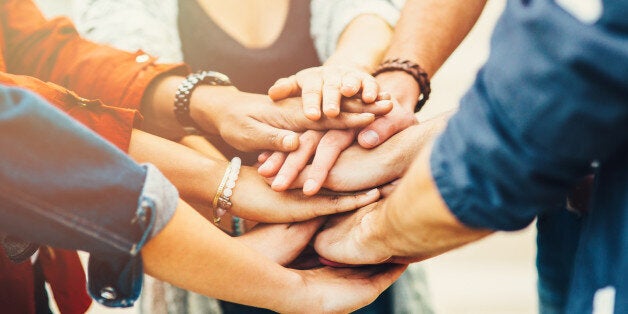 A group of friends putting their hand one over another.