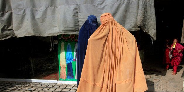 Afghan women, clad in burqas, stand outside a shop at a market in Peshawar, Pakistan June 29, 2016. REUTERS/Fayaz Aziz