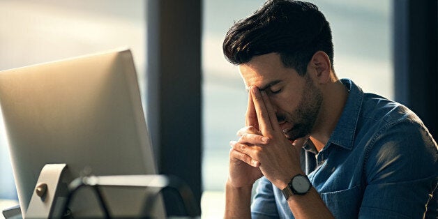 Shot of a young businessman experiencing stress during a late night at work