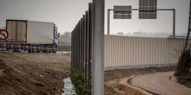 A photo taken on December 13, 2016 in Calais, shows a four-metre-high (13-foot) wall, running along a kilometre-long stretch of the main road leading to Calais port, aimed at stopping migrants from the former Calais 'jungle' camp who attempt to reach its shores. The wall was built to boost a network of wire fences that had failed to prevent near nightly attempts by migrants to waylay trucks en route to Europe's second-busiest port. Calais has for years been a staging post for attempts by migrants to sneak into Britain by stowing away on trucks or trains crossing the Channel. / AFP / PHILIPPE HUGUEN (Photo credit should read PHILIPPE HUGUEN/AFP/Getty Images)