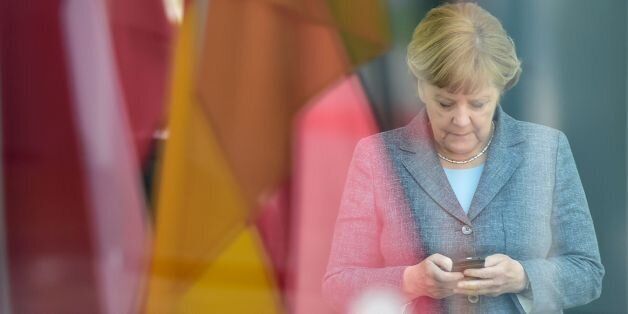 German chancellor Angela Merkel looks at her smartphone while waiting at the chancellery for the arrival of the Latvian Prime Minister in Berlin, on April 29, 2016. / AFP / John MACDOUGALL (Photo credit should read JOHN MACDOUGALL/AFP/Getty Images)