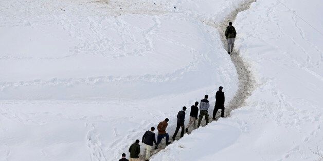 Afghan survivors of an avalanche walk in the Abdullah Khil village of the Dara district of Panjshir province March 1, 2015. More than 180 people have been killed in north Afghanistan in some of the worst avalanches there for 30 years, officials said on Thursday, with heavy snow set to last for two more days after an unusually dry winter led to fears of drought. REUTERS/Omar Sobhani (AFGHANISTAN - Tags: DISASTER ENVIRONMENT TPX IMAGES OF THE DAY)
