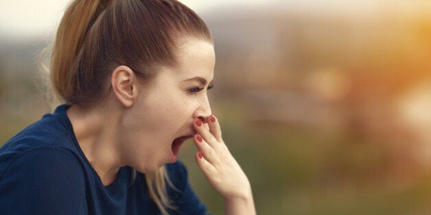 side view of young woman being tired and yawning,photo taken outdoors.sleepy and exhausted.