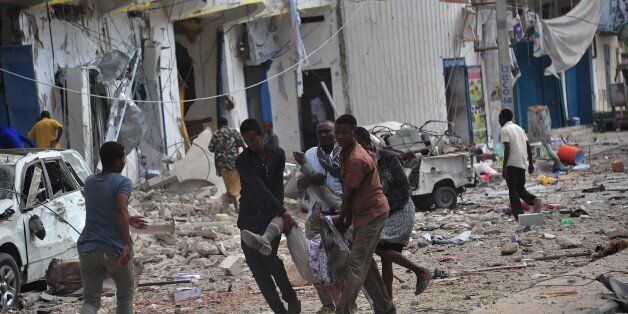 Residents carry an injured man wounded during a complex attack targeting Mogadishu hotel on 25 January 2017. At least seven people were killed after two car bombs exploded outside a popular Mogadishu hotel on Wednesday, and gunmen forced their way inside the building and opened fire, police said / AFP / MOHAMED ABDIWAHAB (Photo credit should read MOHAMED ABDIWAHAB/AFP/Getty Images)