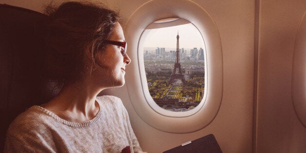 Smiling woman enjoying Paris from the airplane window