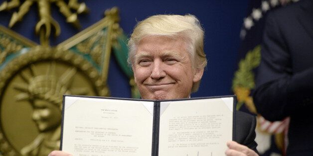 U.S. President Donald Trump holds up signed executive orders in the Hall of Heroes at the Department of Defense in Arlington, Virginia, U.S. on Friday, Jan. 27, 2017. Trump signed an executive action on Friday to establish new vetting procedures for some people seeking to enter the U.S., saying the measure would prevent terrorists from being admitted into the country. Photographer: Olivier Douliery/Pool via Bloomberg