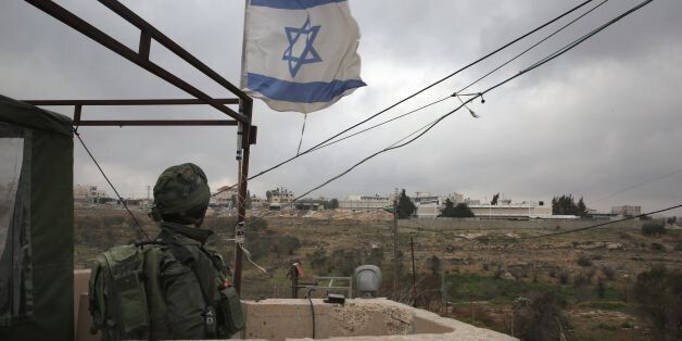 This photo taken on January 25, 2017 shows an Israeli soldier standing guard in a monitoring cabin in the Israeli settlement of Beit El near the West Bank city of Ramallah (background).Israel has moved immediately to take advantage of US President Donald Trump's pledges of support, announcing a major settlement expansion that deeply concerns those hoping to salvage a two-state solution with the Palestinians. / AFP / - / MENAHEM KAHANA (Photo credit should read MENAHEM KAHANA/AFP/Getty Images)