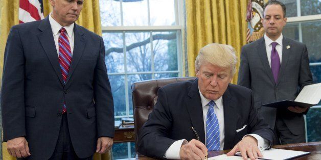 US President Donald Trump signs an executive order withdrawing the US from the Trans-Pacific Partnership alongside US Vice President Mike Pence (L) and White House Chief of Staff Reince Priebus (R) in the Oval Office of the White House in Washington, DC, January 23, 2017.Trump the decree Monday that effectively ends US participation in a sweeping trans-Pacific free trade agreement negotiated under former president Barack Obama. / AFP / SAUL LOEB (Photo credit should read SAUL LOEB/AFP/Get