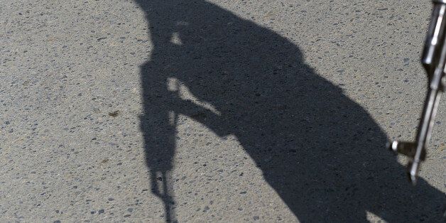 The shadow of an Afghan policeman falls onto the ground as he keeps watch near the largest US military base in Bagram, 50 km north of Kabul, after an explosion on November 12, 2016. Four people were killed November 12 in an explosion inside the largest US military base in Afghanistan, NATO said, with local officials blaming a suicide attacker posing as a labourer for the major security breach. / AFP / SHAH MARAI (Photo credit should read SHAH MARAI/AFP/Getty Images)