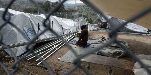 A man prays in the Moria migrant camp on the Greek island of Lesbos on December 30, 2016.There are over 60,000 refugees and migrants trapped in Greece after EU and Balkan countries further north shut their borders nearly a year ago. / AFP / STR (Photo credit should read STR/AFP/Getty Images)