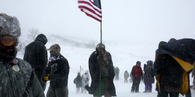 A man holds an American flag while marching with veterans and activists outside the Oceti Sakowin camp where