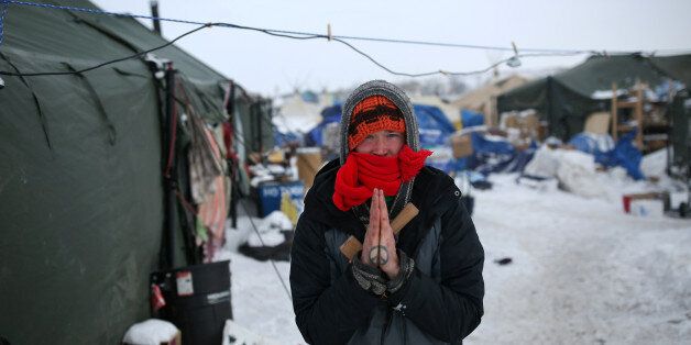 An activist with a peace sign tattoo on his hands poses for a photograph inside the Rosebud camp where