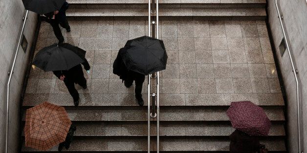Commuters carry umbrellas as they make their way in and out of Syntagma metro station in Athens January 28, 2014. REUTERS/Yorgos Karahalis (GREECE - Tags: SOCIETY ENVIRONMENT TRANSPORT)