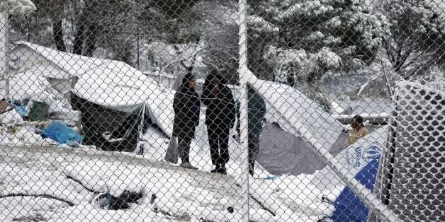 Migrants stand next to their tents at the Moria hotspot on the island of Lesbos , following heavy snowfalls on January 7, 2017. The number of migrants arriving in Europe by two main sea routes in 2016 plunged by almost two-thirds to 364,000 compared with the previous year, EU border agency Frontex said Friday. Frontex pointed to an EU border deal with Turkey which came into effect in March as having paved the way to a massive decline in the arrival of Syrian refugees and other migrants in Greece. / AFP / STR (Photo credit should read STR/AFP/Getty Images)