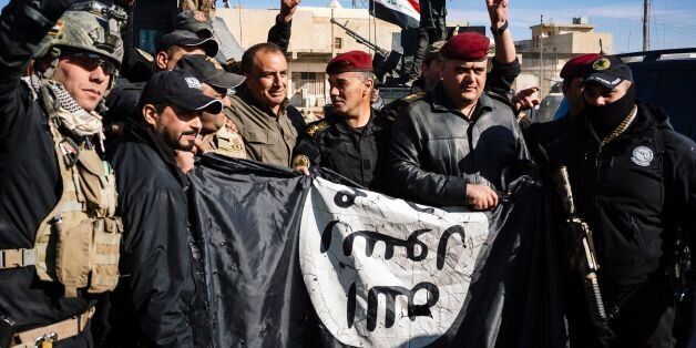 Members of the Iraqi special forces Counter Terrorism Service (CTS) hold an Islamic State (IS) group flag as they celebrate in their military base in the town of Bartalla on January 18, 2017 after a top Iraqi commander announced that have they fully retaken east Mosul from the IS group, three months after a huge offensive against the jihadist bastion was launched.Elite forces have in recent days entered the last neighbourhoods on the eastern side of Mosul, on the left bank of the Tigris River that runs through the city. / AFP / Dimitar DILKOFF (Photo credit should read DIMITAR DILKOFF/AFP/Getty Images)
