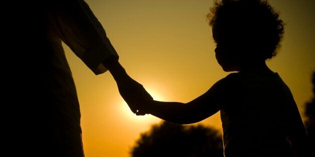 Royalty Free stock photo of mother and daughter holding hands facing the sunset. Applied warming effect and vignette effect in post processing