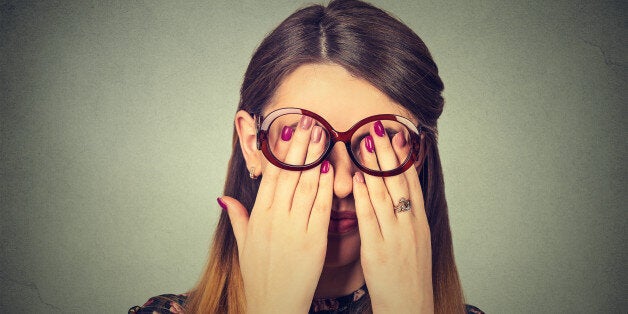 Closeup portrait young woman in glasses covering face eyes using her both hands isolated on gray wall background