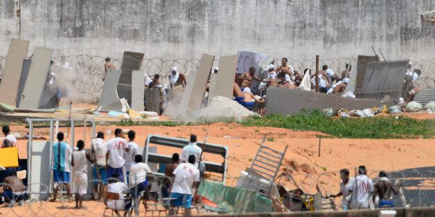 Prisoners cover themselves using makeshift shields as riot police agents (out of frame) fire rubber bullets during a rebellion at the Alcacuz Penitentiary Center near Natal in Rio Grande do Norte, Brazil on January 17, 2017. Brazilian police fired rubber bullets Tuesday at inmates who have taken over a jail where dozens were massacred over the weekend in the latest in a string of prison riots. Police positioned on top of the outer walls of the Alcacuz jail near the northeastern city of Natal fired at a crowd of inmates who had taken control of part of the complex. A total of 26 prisoners were killed in Alcacuz -- many of them beheaded -- during a violent riot that broke out late Saturday, according to officials. / AFP / Andressa Anholete (Photo credit should read ANDRESSA ANHOLETE/AFP/Getty Images)