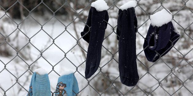 Socks that belong to stranded refugees are covered in snow as they hang on a fence during a snowstorm at a refugee camp north of Athens, Greece January 10, 2017.REUTERS/Yannis Behrakis