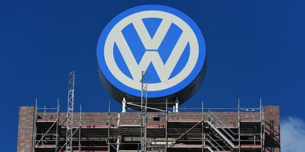 A worker stands on a scaffold lift, under a giant VolksWagen logo at VolksWagen's original headquarters building, now under renovation in Wolfsburg, northern Germany, on September 30, 2015. German auto giant Volkswagen shifted up a gear Wednesday in its plans to recall millions of cars fitted with pollution-cheating software as it boosted efforts to find the masterminds behind the scam. AFP PHOTO / JOHN MACDOUGALL / AFP / JOHN MACDOUGALL (Photo credit should read JOHN MACDOUGALL/AFP/Getty Images)