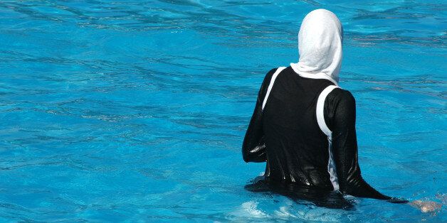Muslim woman with headress and clothes swimming in a swimming pool