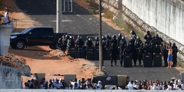 Riot police agents group and approach to negociate with an inmate's delegate (R) during a rebellion at the Alcacuz Penitentiary Center near Natal, Rio Grande do Norte state, northeastern Brazil on January 16, 2017.The latest in a string of brutal prison massacres involving suspected gang members in Brazil has killed 26 inmates, most of whom were beheaded. The bloodbath erupted Saturday night in the overcrowded Alcacuz prison in the northeastern state of Rio Grande do Norte. Similar violence at o