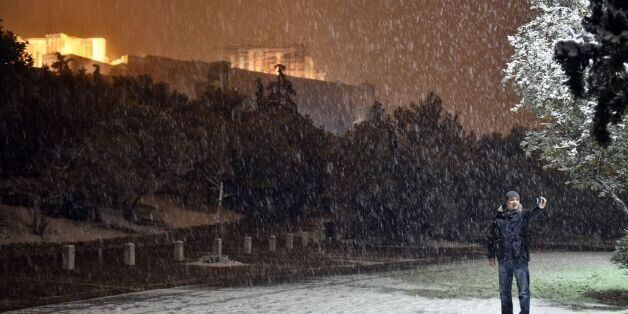 A man takes a selfie with the Acropolis in the background during heavy snowfall in central Athens on the night of January 9, 2017.A cold snap gripping Europe has killed more than 30 people in recent days, left thousands of travellers stranded in snow-covered Turkey and brought fresh misery for migrants and the homeless. / AFP / LOUISA GOULIAMAKI (Photo credit should read LOUISA GOULIAMAKI/AFP/Getty Images)