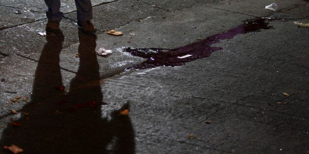 The shadow of a police officer is cast near a puddle of blood at a crime scene outside a nightclub in an upscale neighborhood of Guadalajara February 12, 2011. A group of hitmen showed up outside the club, started shooting and threw a grenade inside the building killing at least seven people and injuring another 30, according to local media. Cartel hitmen are murdering rivals and terrifying residents across Mexico's second city Guadalajara as it prepares to host the Pan American Games in a deepening of the country's drugs war. REUTERS/Alejandro Acosta (MEXICO - Tags: CRIME LAW CIVIL UNREST)