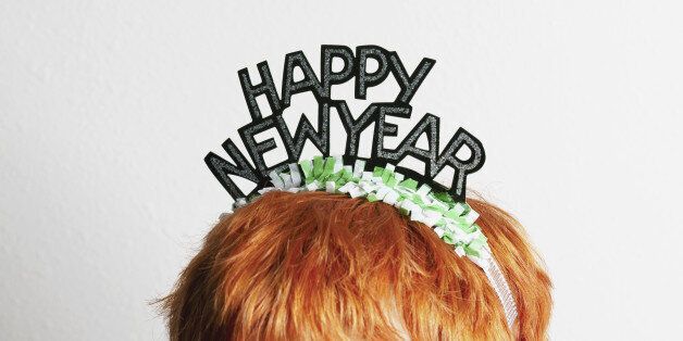 A woman wearing a party tiara with Happy New Year on it, top of head